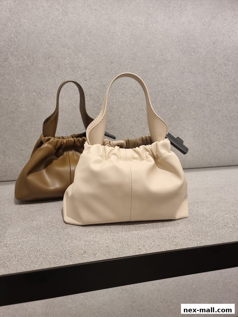 Two stylish ruched handbags, one cream and one brown, displayed on a shelf.