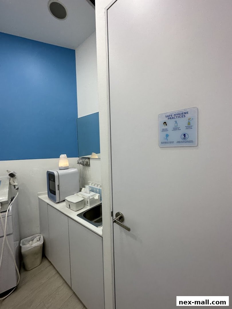 Interior shot of a clean, modern treatment room with a sink and hygiene signage.