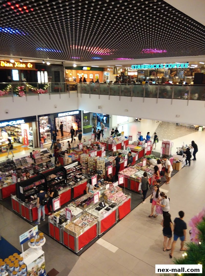 An overhead view of a busy shopping mall with various retail displays and shoppers.