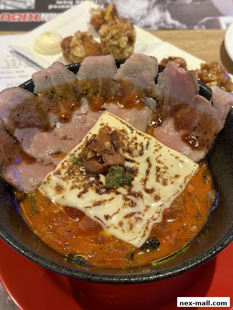 A close-up of a ramen bowl with sliced meat, melted cheese, and a rich broth.