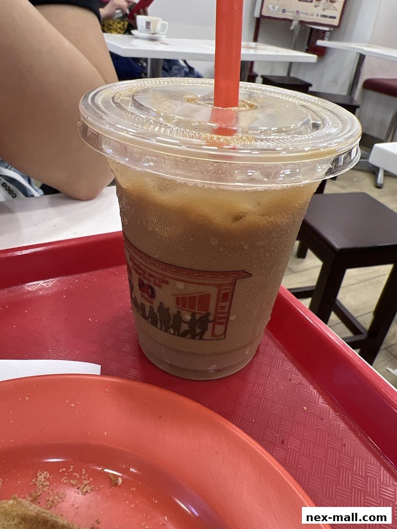 A close-up of a refreshing iced coffee drink with a red straw on a red tray.