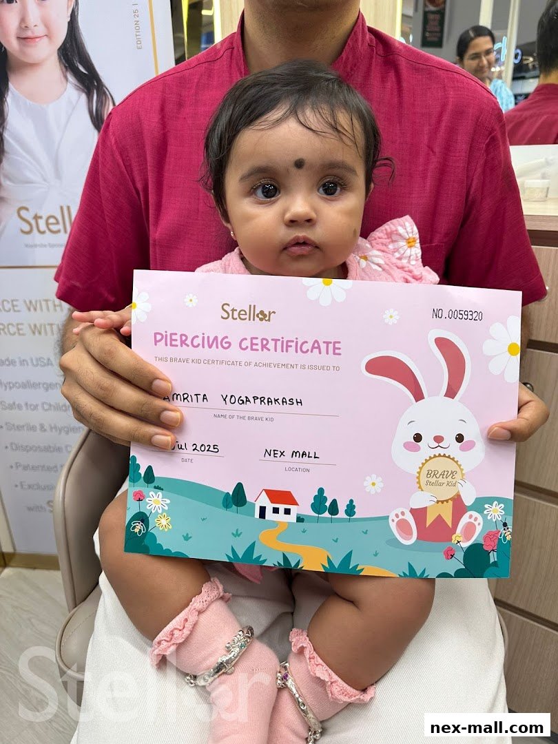 A baby proudly holds a Stellar Piercing Certificate with a parent behind them.