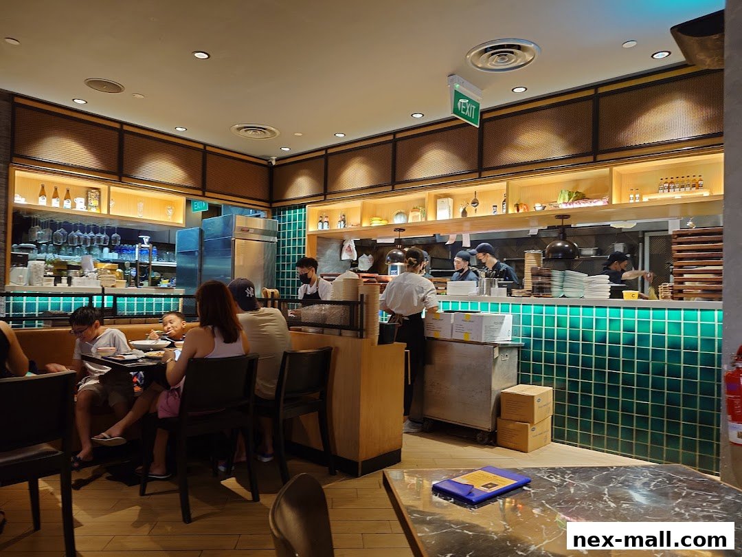 Diners seated at tables in a restaurant with staff working behind a counter.
