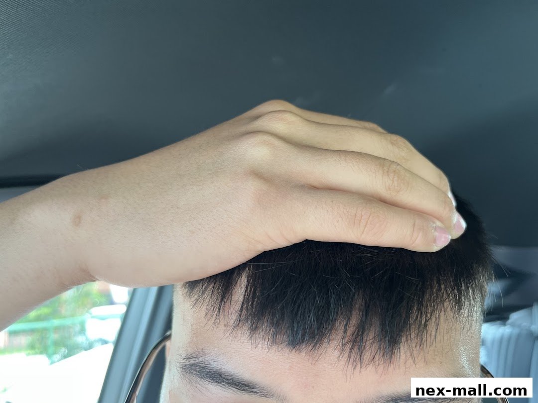 A person's hand is resting on their forehead, showing their hair and eyebrows.