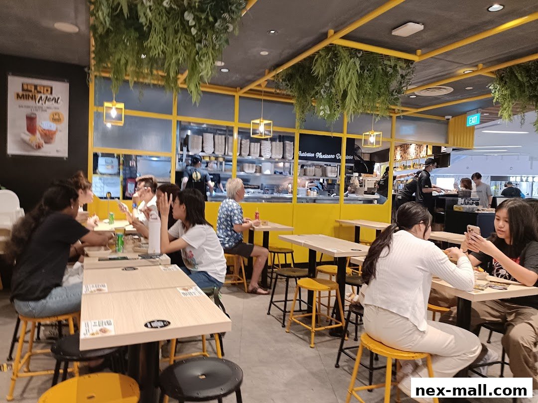 People dining at tables inside a brightly lit Guzman y Gomez restaurant with yellow accents.