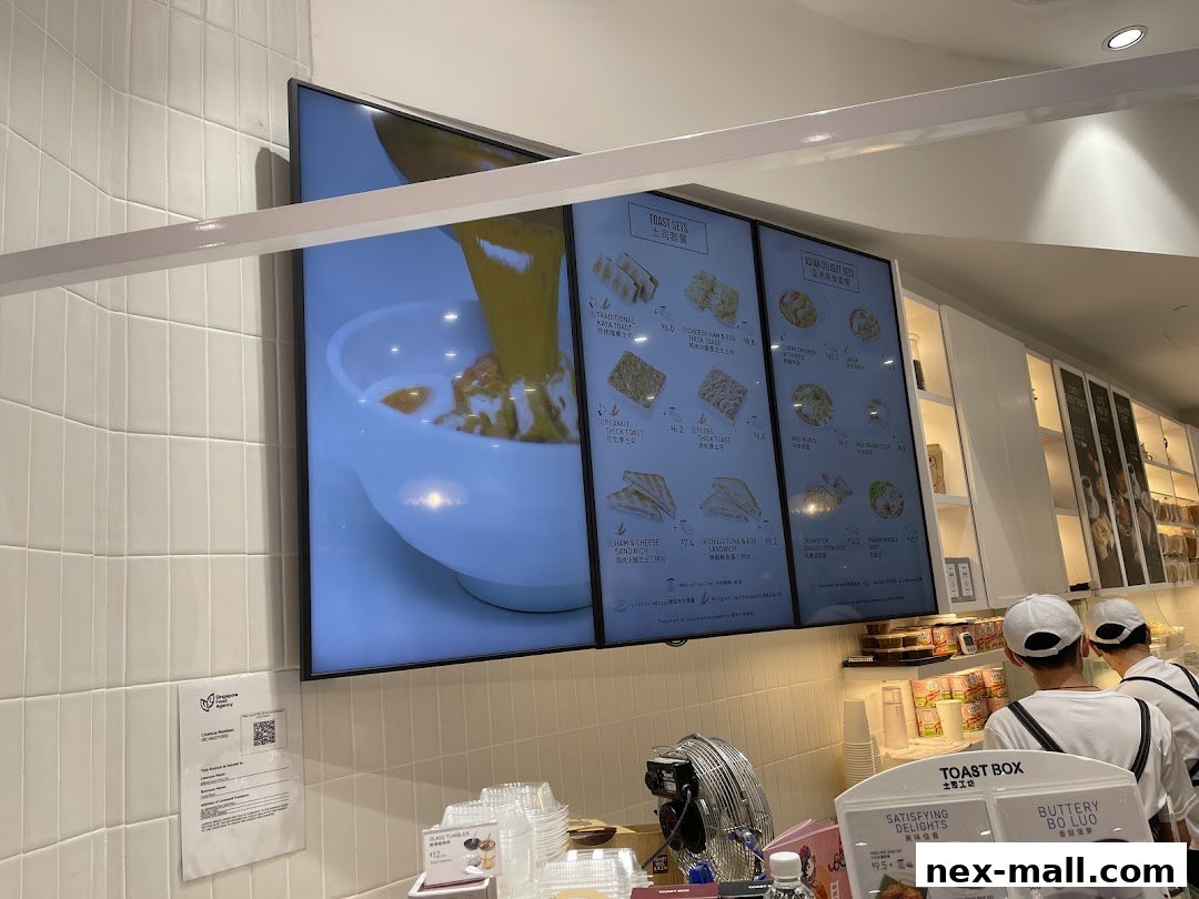 Digital menu boards displaying various toast sets and Asian delights at Toast Box.