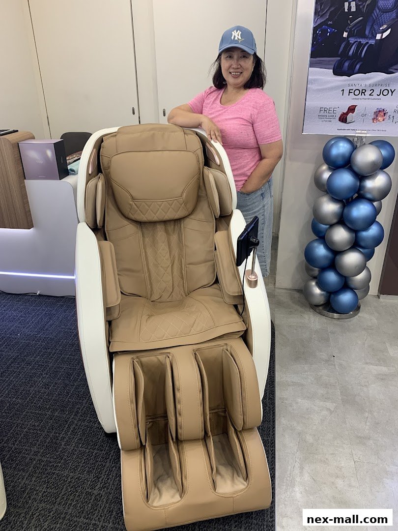 A woman stands next to a luxurious massage chair in a retail store.