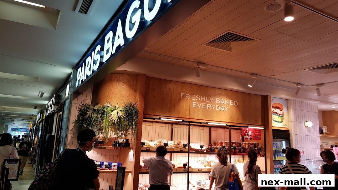 People browsing at Paris Baguette NEX, a bakery with a display of fresh baked goods.