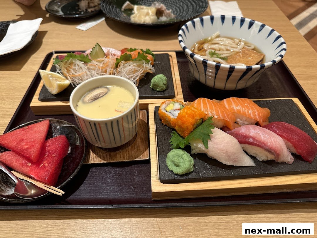A tray of Japanese food including sushi, sashimi, chawanmushi, udon, and watermelon.