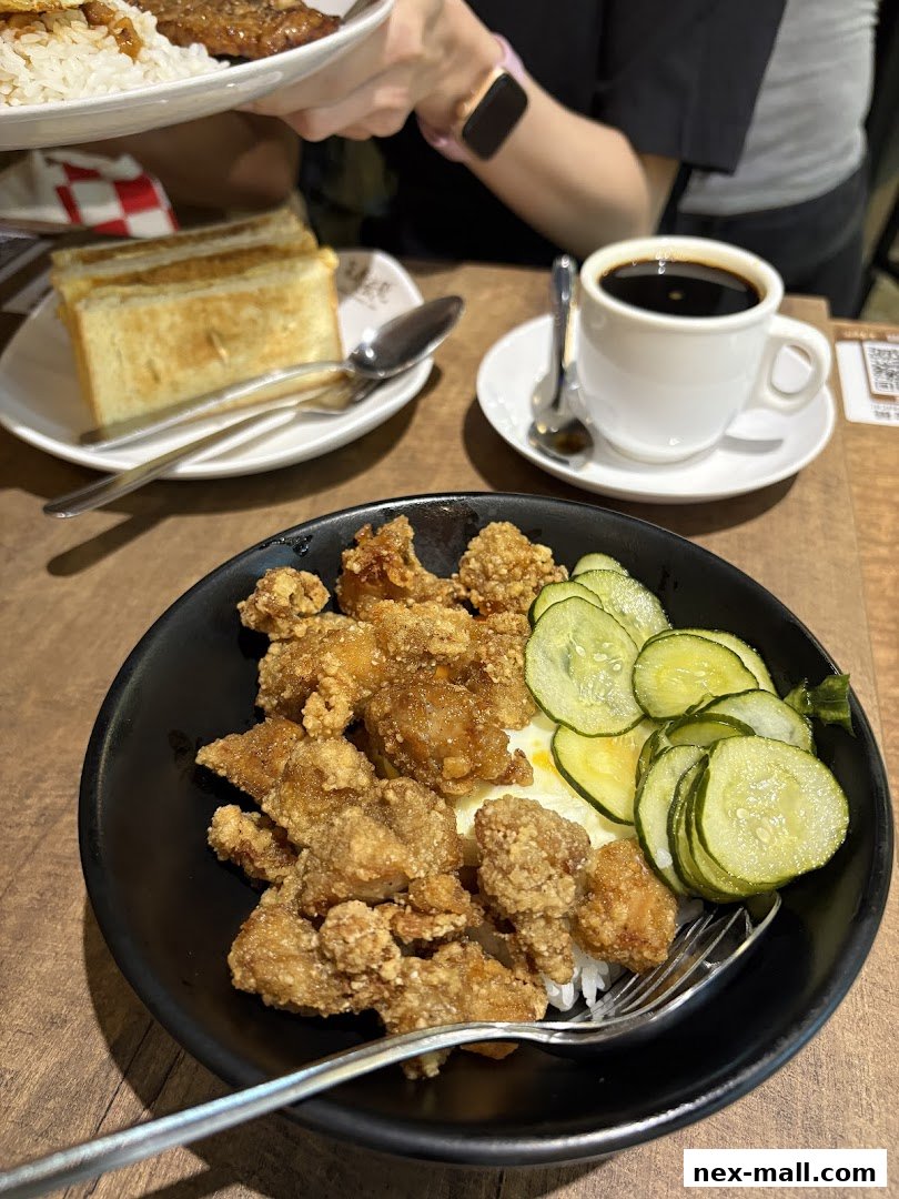 A close-up of a delicious meal featuring crispy fried chicken, rice, pickles, and toast with coffee.