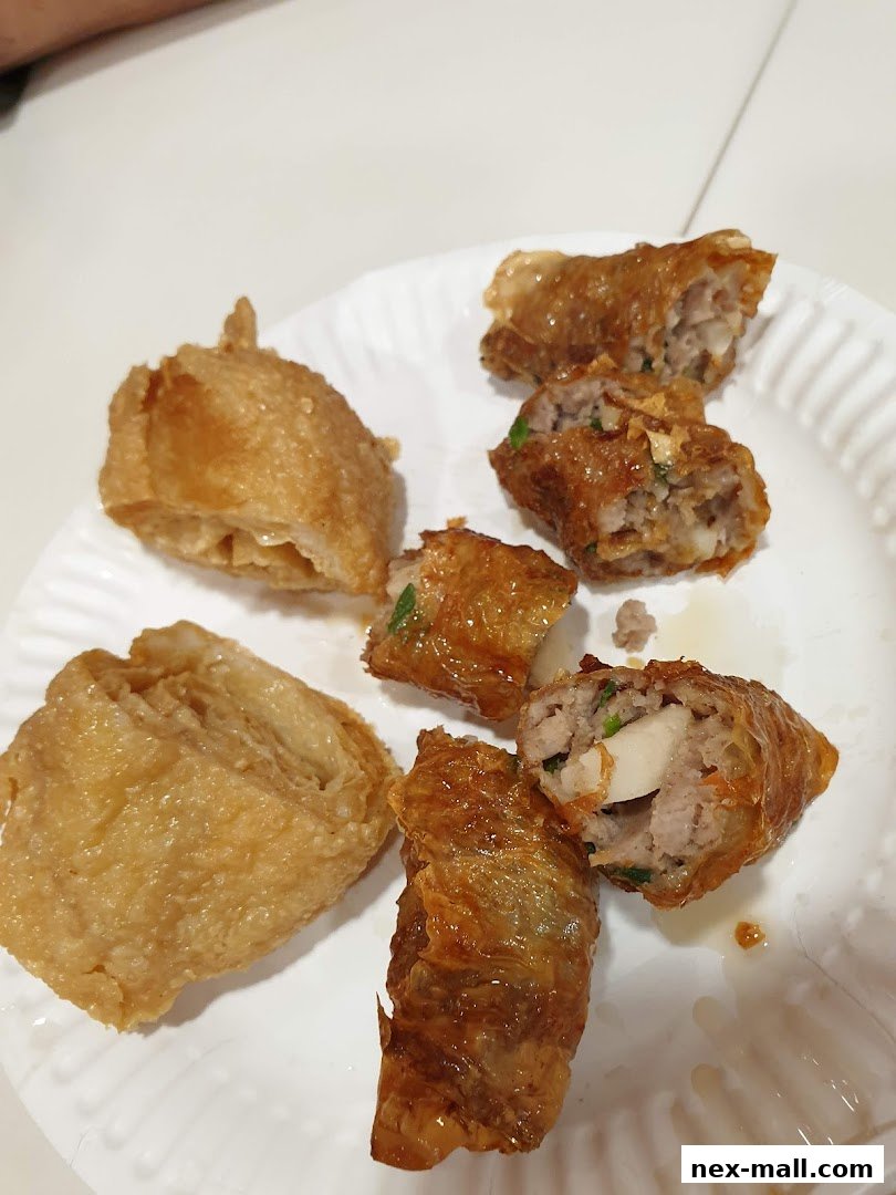 A white plate filled with crispy fried dim sum items, including bean curd rolls and meat-filled rolls.