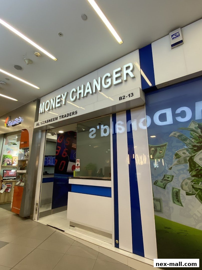 The exterior of AL Thasneem Traders Money Changer shop with prominent signage and currency exchange rates displayed.