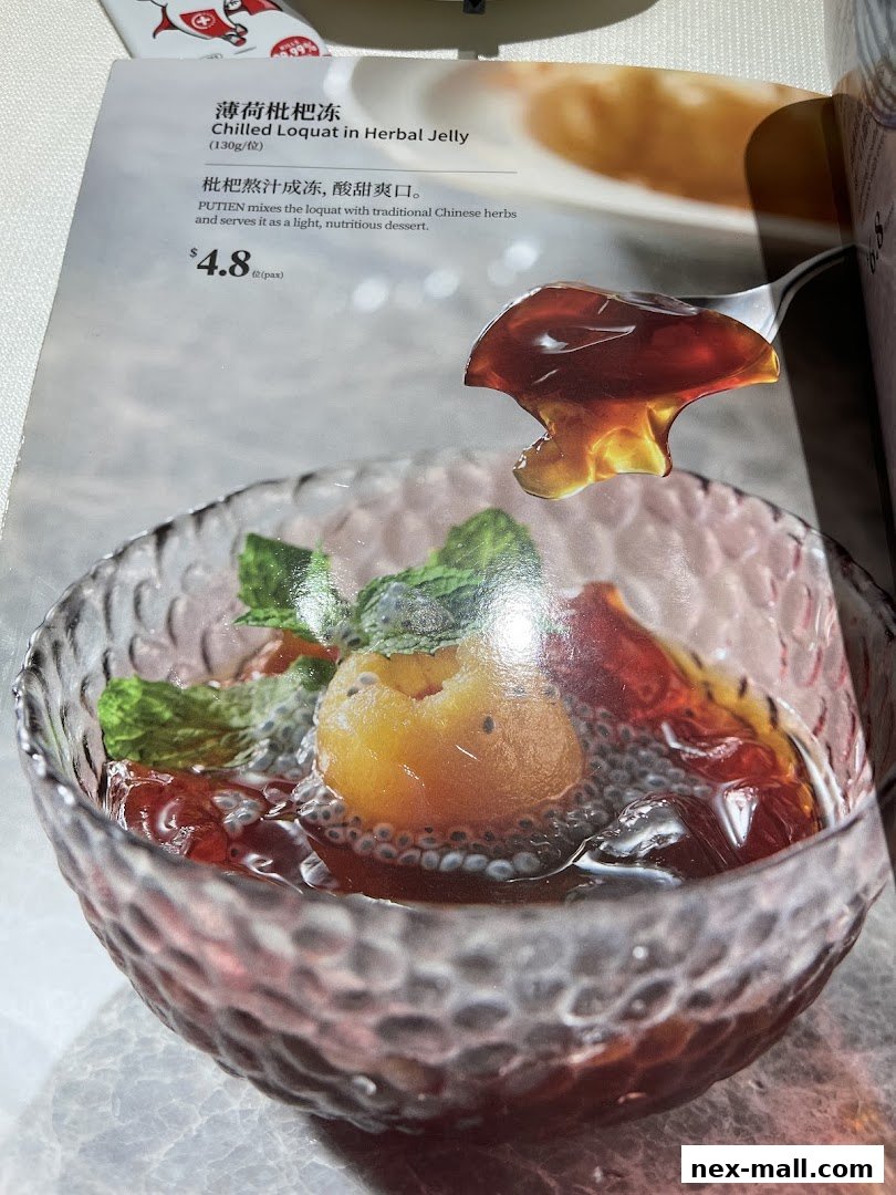 A close-up of a chilled loquat in herbal jelly dessert with mint leaves.