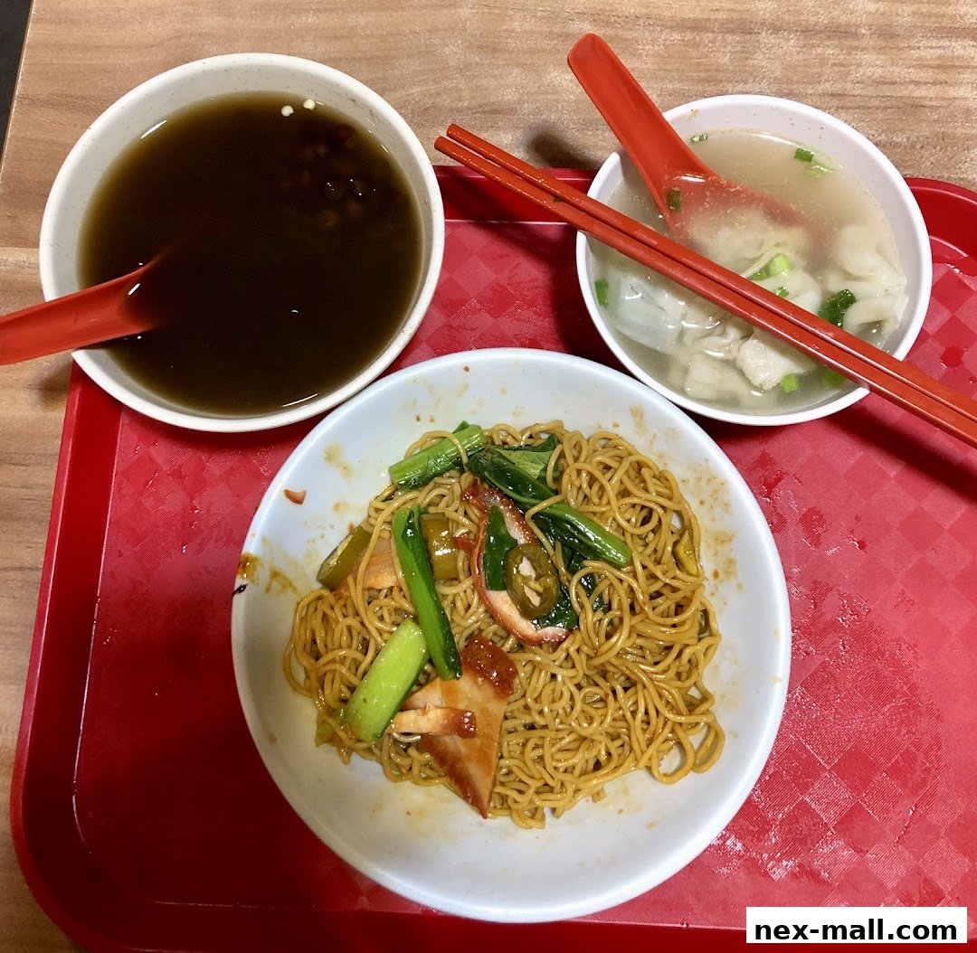 A bowl of noodles with char siu and vegetables, served with soup and a side of wonton soup.