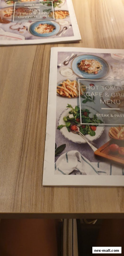 A menu from Hot Tomato Cafe & Grill featuring various dishes like pasta, fries, and salads.