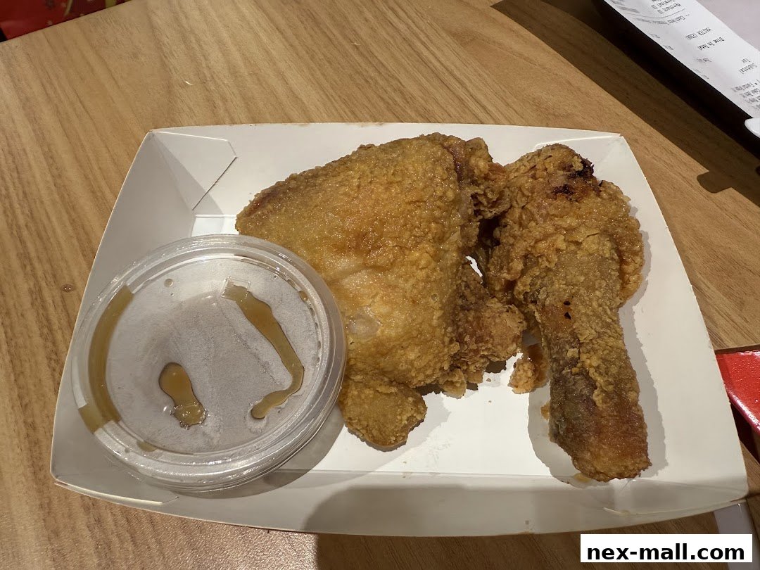 A serving of crispy fried chicken with a side of gravy in a white takeout box.