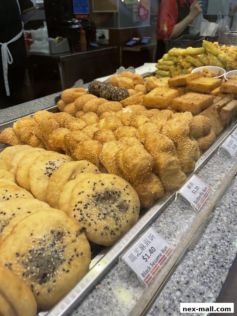 A display of freshly fried pastries and snacks, including sesame buns and fried tofu.