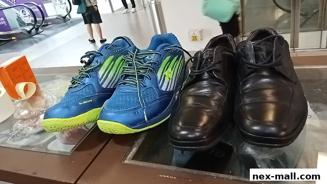 A display of athletic shoes and formal shoes on a glass surface.