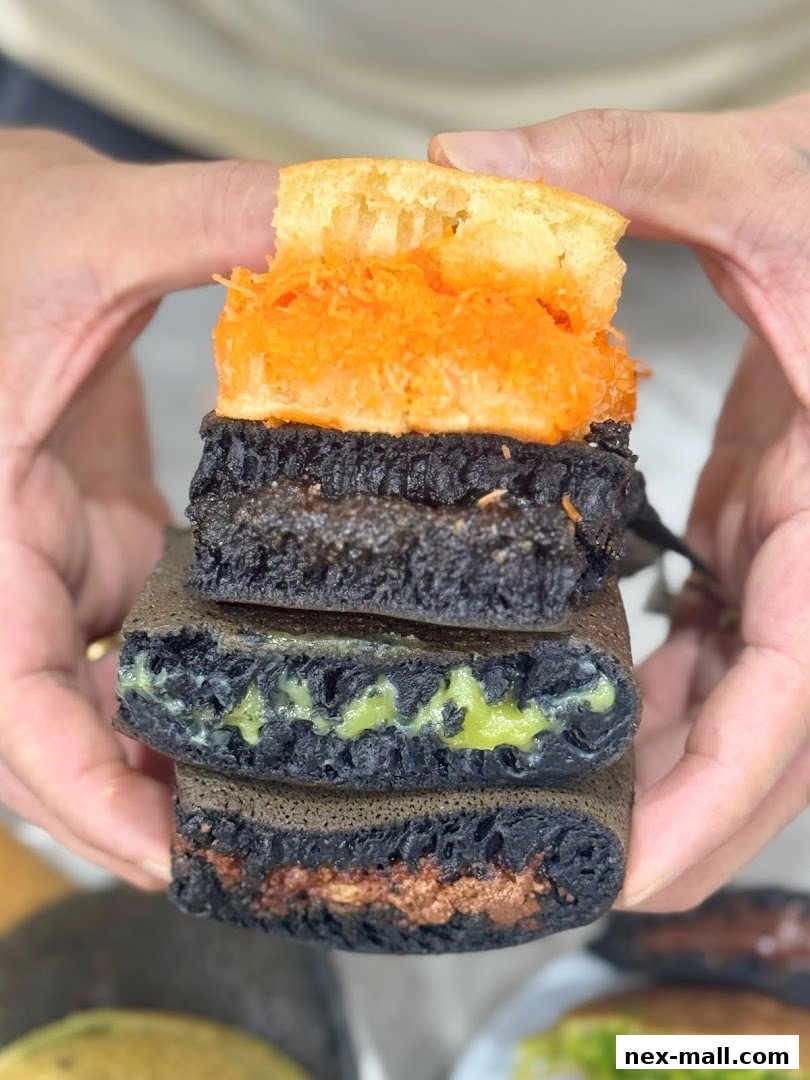 A close-up shot of stacked pancakes with various fillings, held by hands.