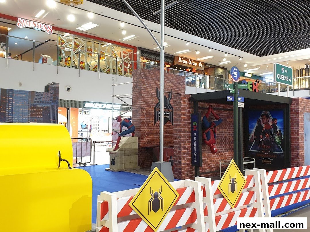A Spiderman-themed display with statues and movie posters in a shopping mall.