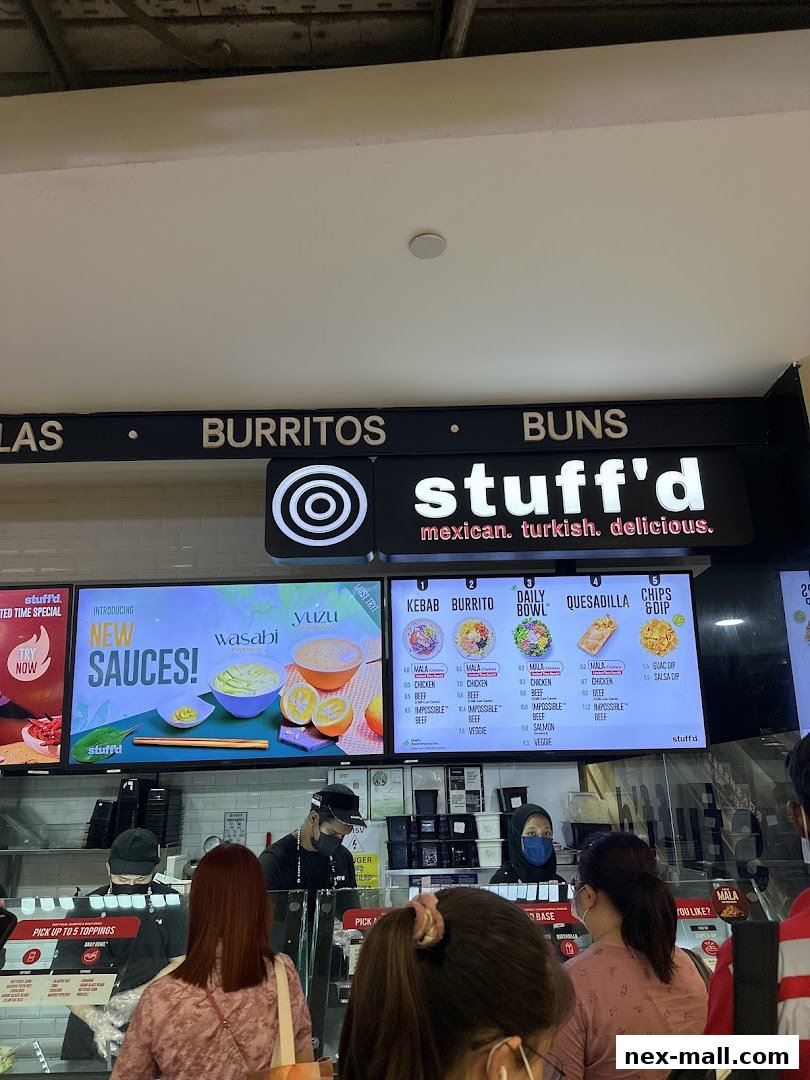 A Stuff'd shop with a menu board displaying burritos, kebabs, and bowls, and customers ordering.