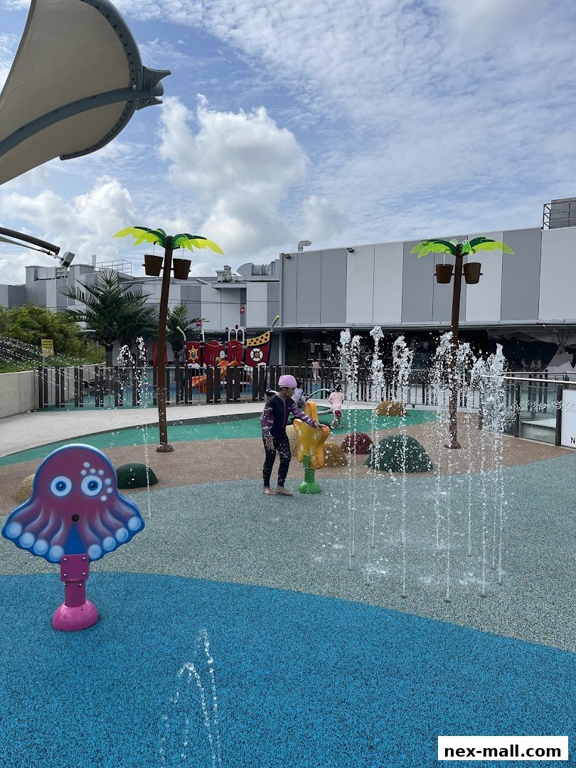 Children playing at an outdoor water playground with colorful structures and fountains.