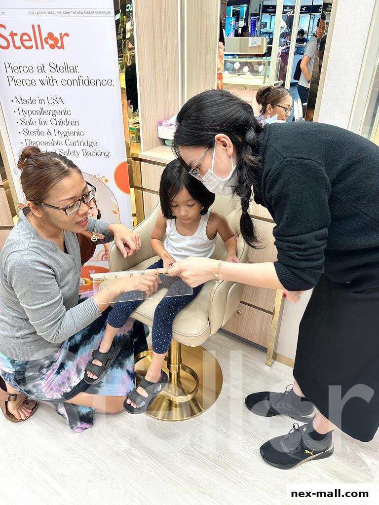 A child is getting their ear pierced by a professional at Stellar NEX Ear Piercing Jewellery.
