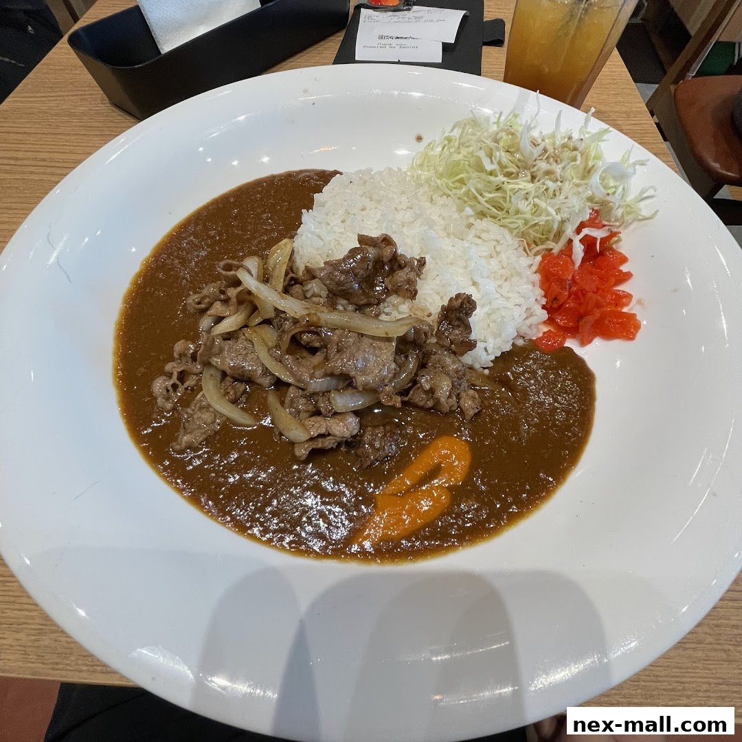 A plate of Japanese curry with rice, beef, onions, and shredded cabbage.