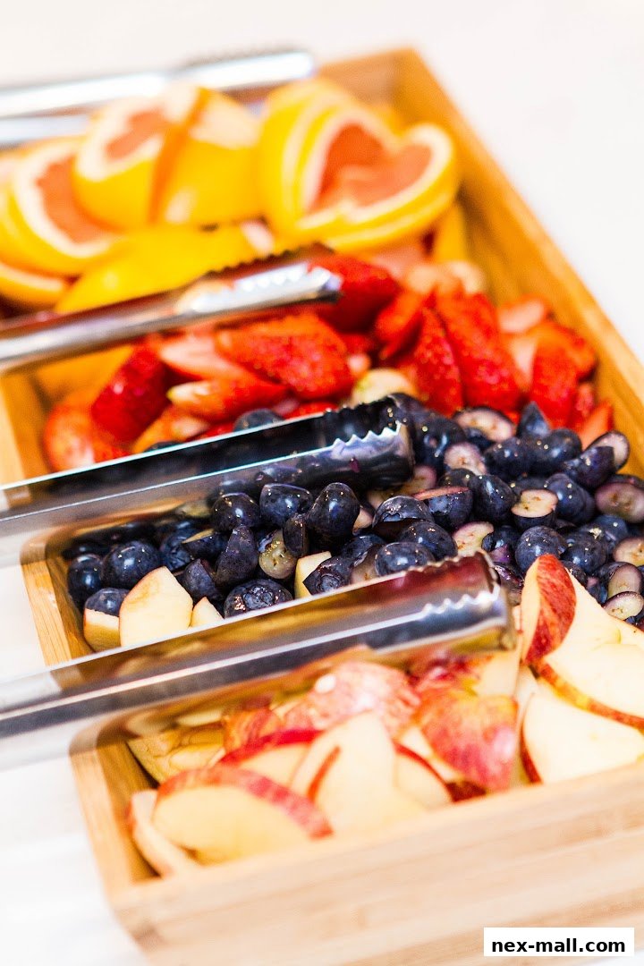 A close-up shot of a variety of fresh fruits, including strawberries, blueberries, grapefruit, and apples, served in wooden trays.