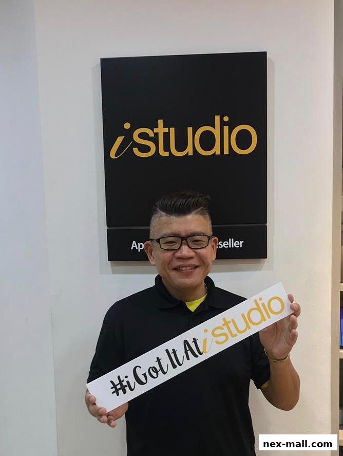 A man holds a sign that says "#iGotItAt studio" in front of an iStudio sign.