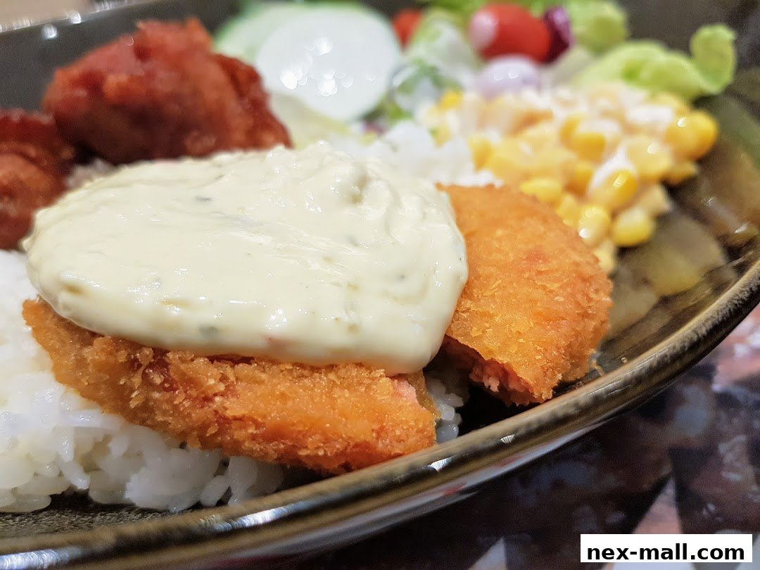A close-up of a Yoshinoya dish featuring crispy fried fish, rice, and a creamy sauce.