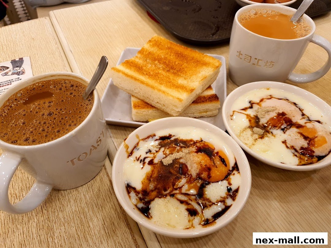 A close-up of a breakfast spread featuring toast, coffee, tea, and soft-boiled eggs with soy sauce.