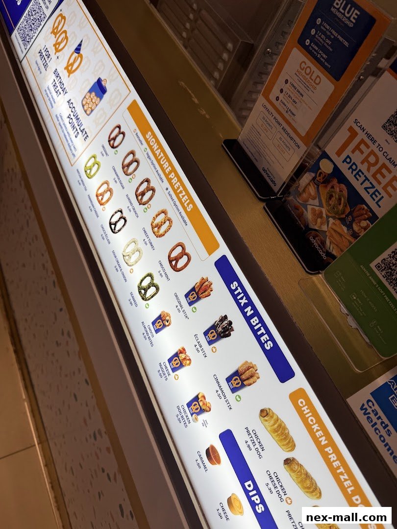 A brightly lit menu board displaying various pretzel items and dips from Auntie Anne's.