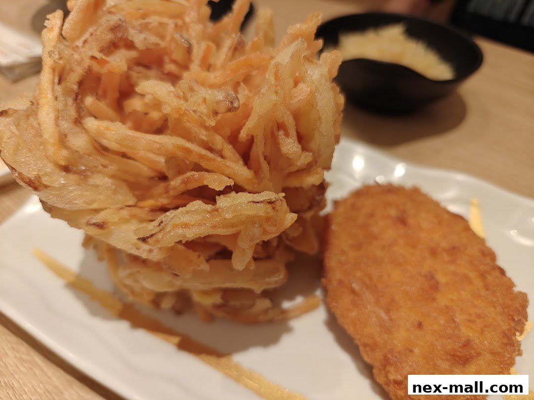 A close-up of crispy fried food items served on a white plate with a small dipping bowl.