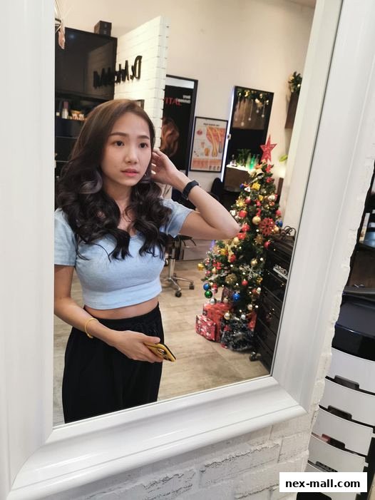 A woman poses in a hair studio with a Christmas tree and salon equipment reflected in a mirror.
