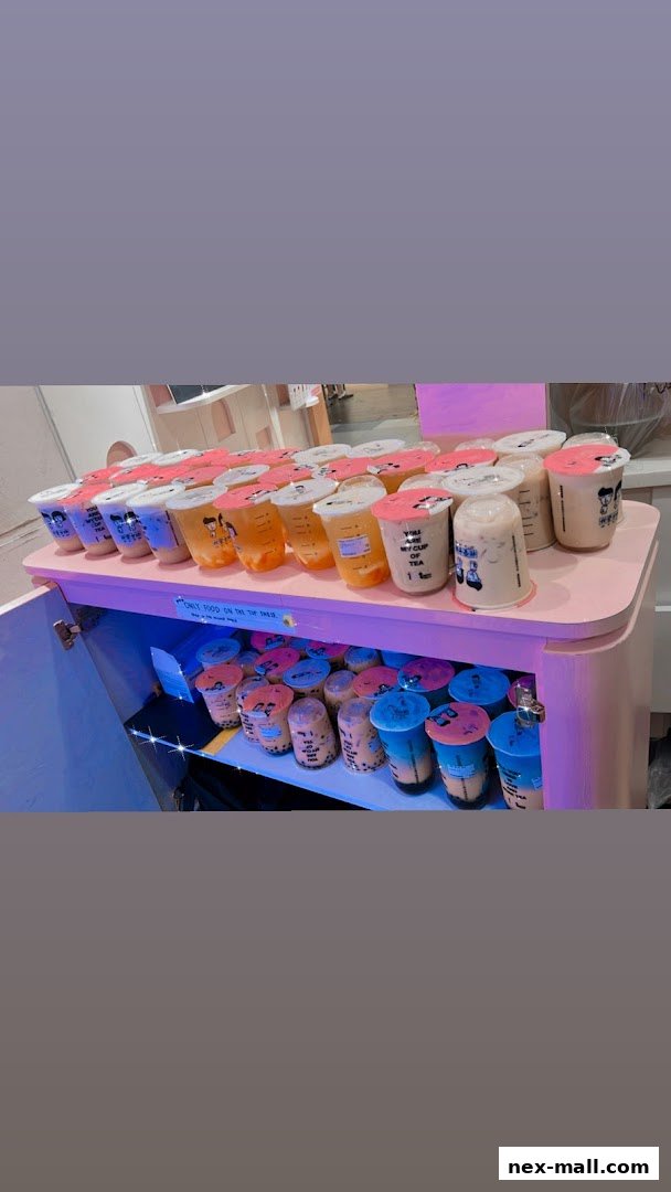 A display of numerous colorful bubble tea drinks in clear cups with pink lids.