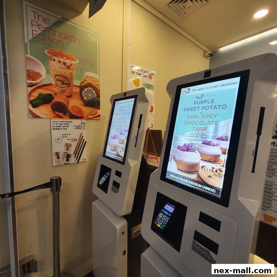 Self-ordering kiosks and promotional posters for bubble tea and tarts at PlayMade.
