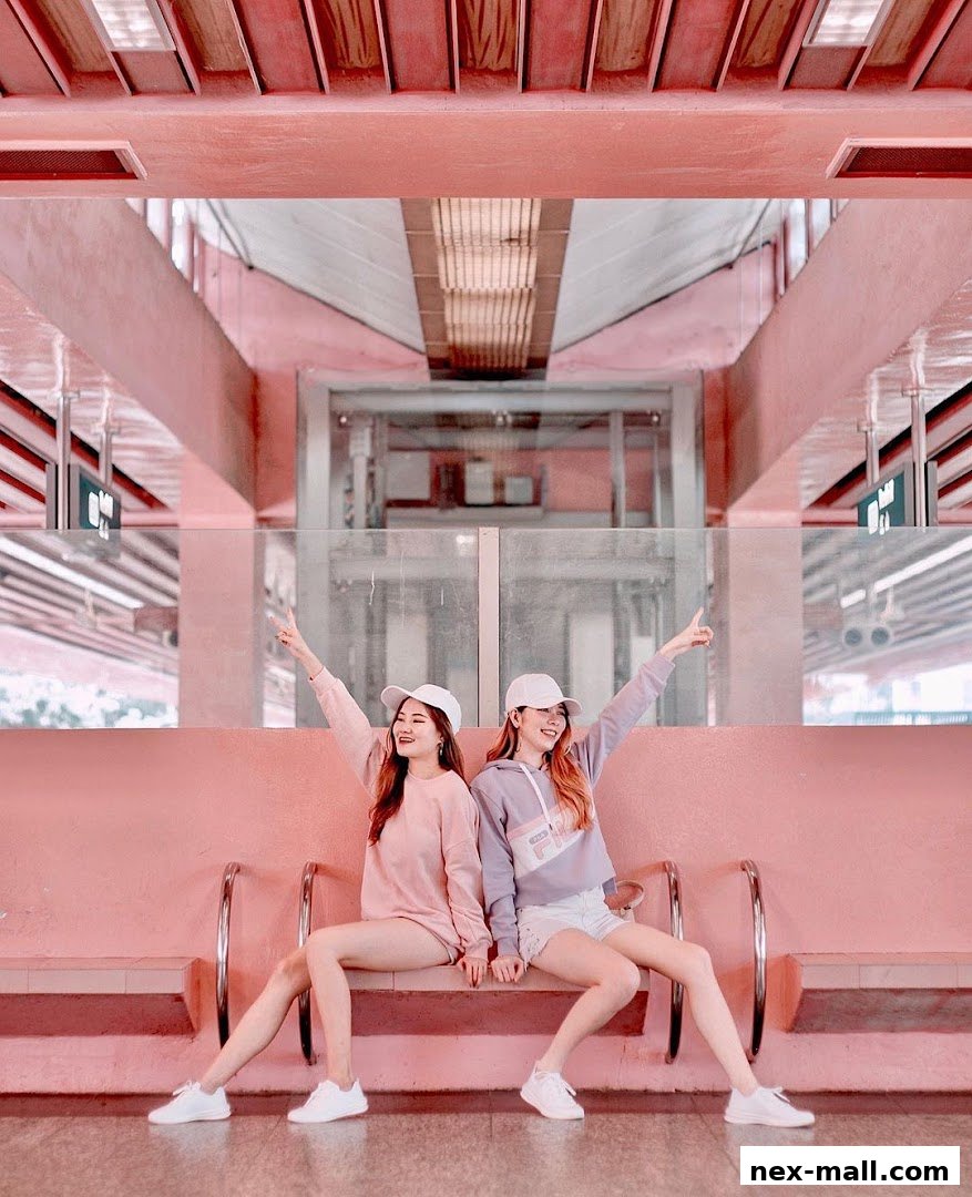 Two young women in casual outfits and caps posing on a pink bench.