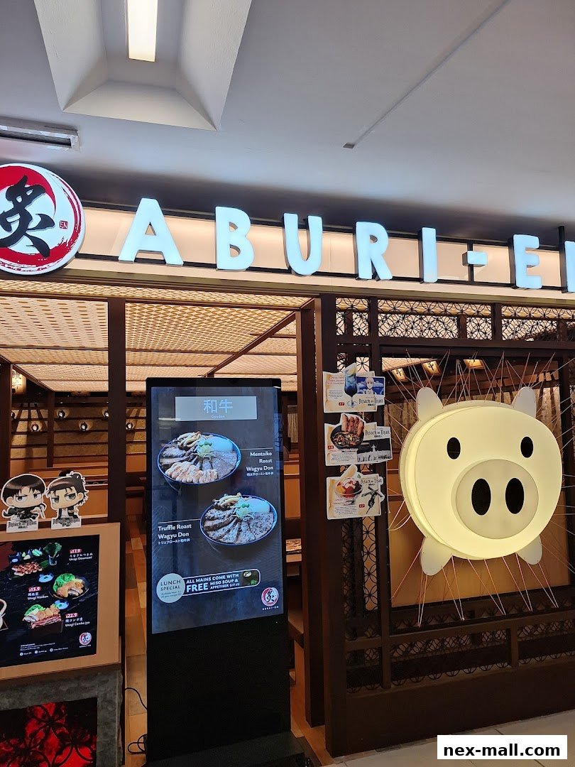 The exterior of Aburi-EN Nex restaurant with illuminated signage and a digital menu display.