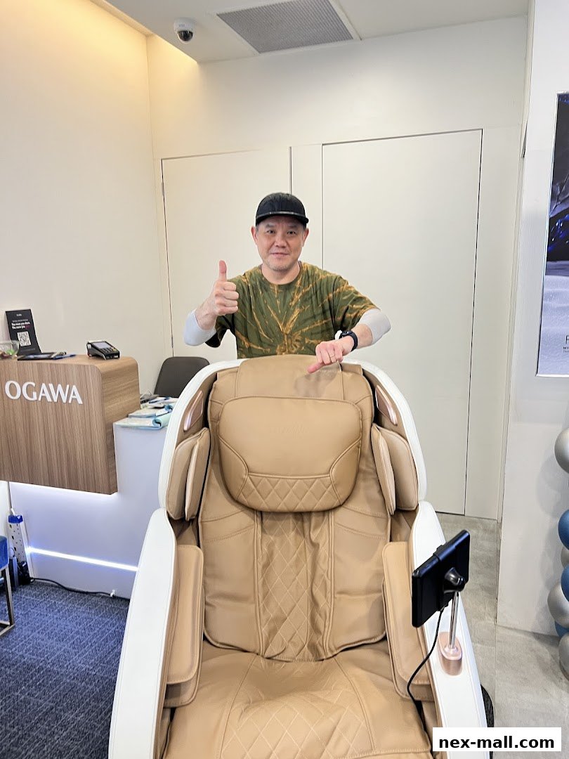 A man gives a thumbs up next to a luxurious massage chair at OGAWA NEX.