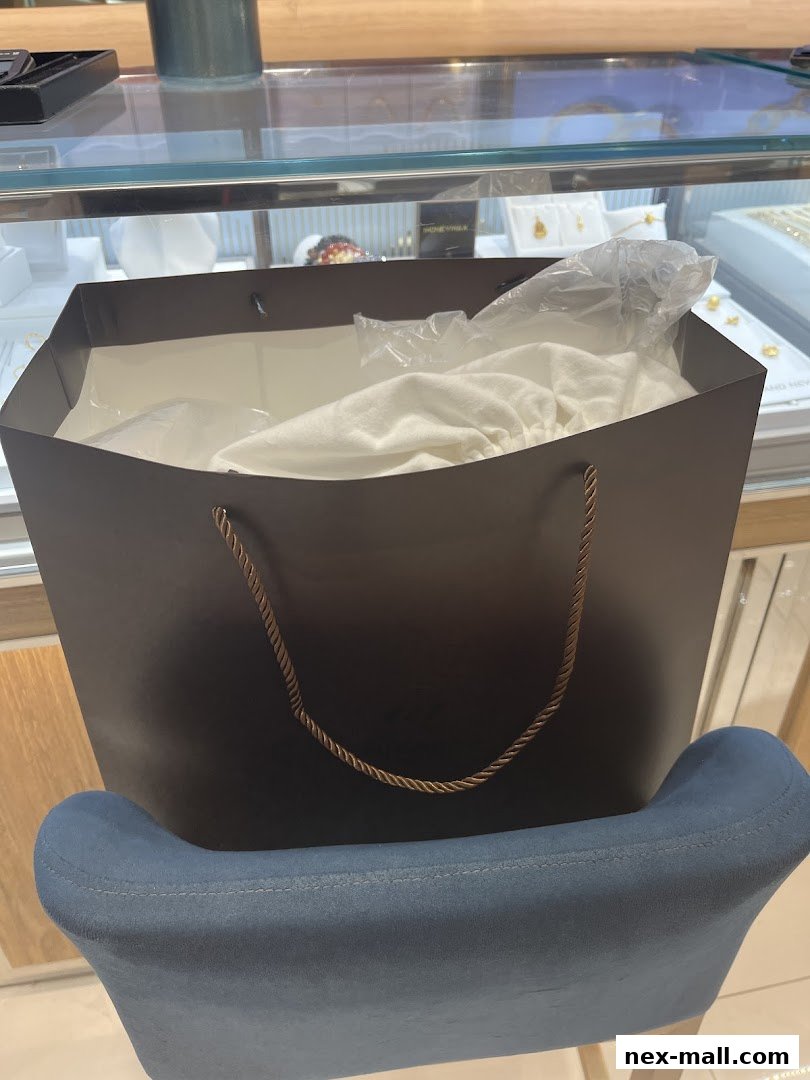 A dark shopping bag filled with white fabric sits on a blue chair in front of a display case.