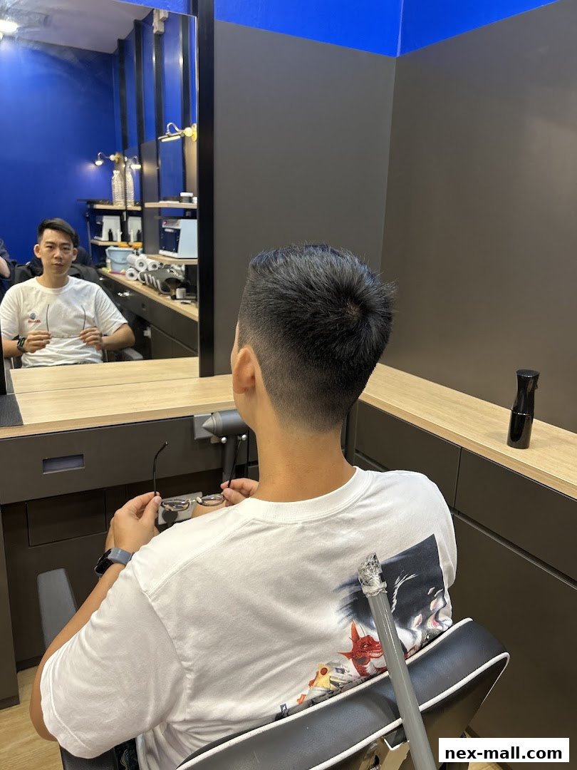 A man sits in a barber chair, looking in the mirror after a haircut.