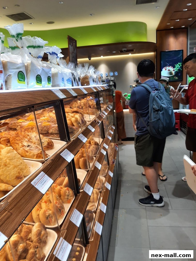 A bakery display case filled with various breads and pastries, with customers browsing.