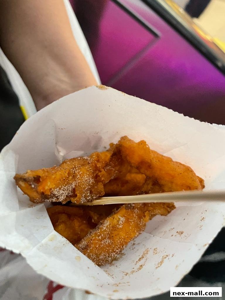 A close-up shot of crispy sweet potato fries dusted with sugar and cinnamon.