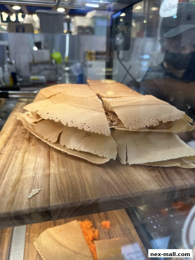 Close-up of freshly made pancakes with a creamy filling on a wooden board.