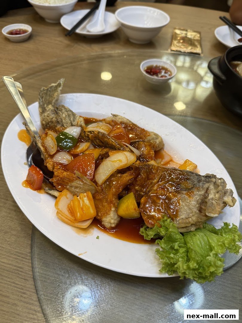 A plate of sweet and sour fish with vegetables and a side of lettuce.