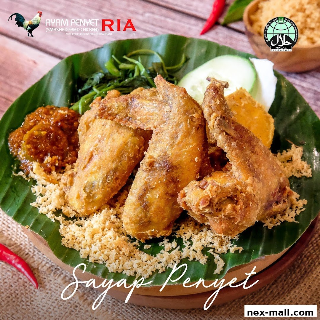 A plate of Ayam Penyet Ria's signature smashed fried chicken wings with rice and chili.