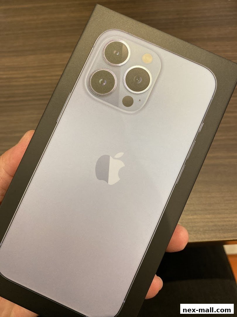A hand holds a box containing a new iPhone with a triple-lens camera system.