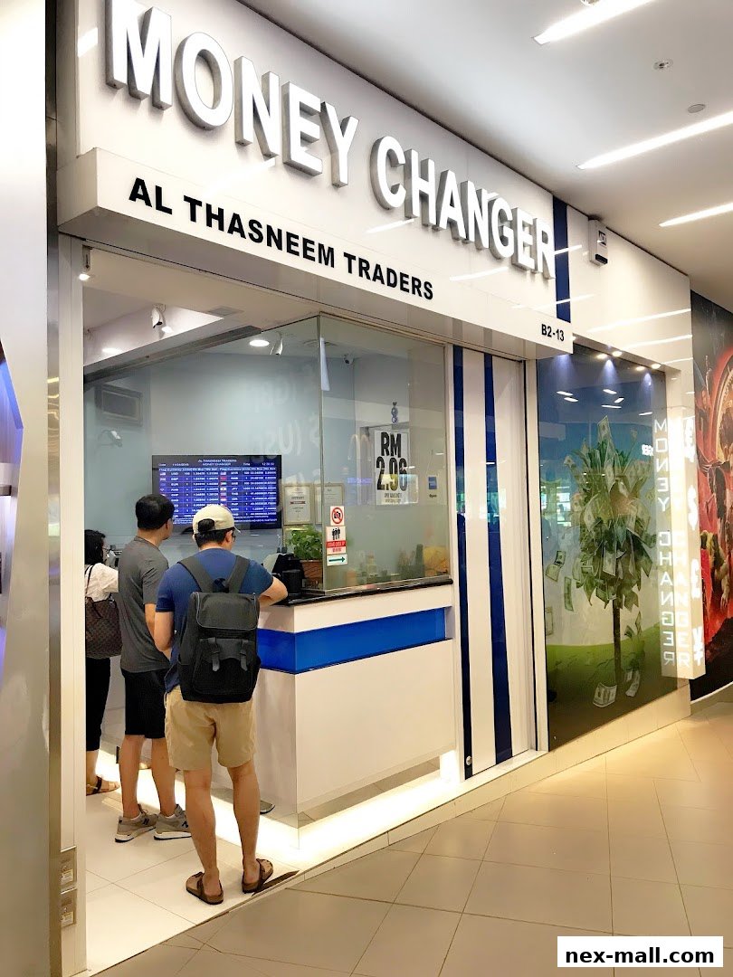 The exterior of AL Thasneem Traders Money Changer shop with customers at the counter.
