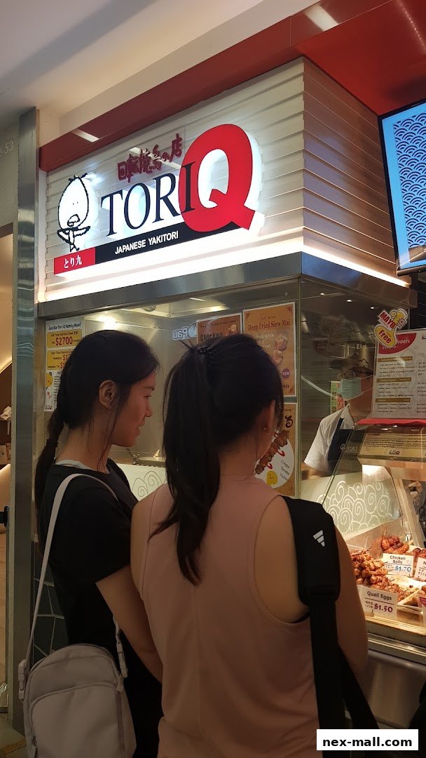 Customers looking at the TORI-Q Japanese Yakitori shop display and menu.